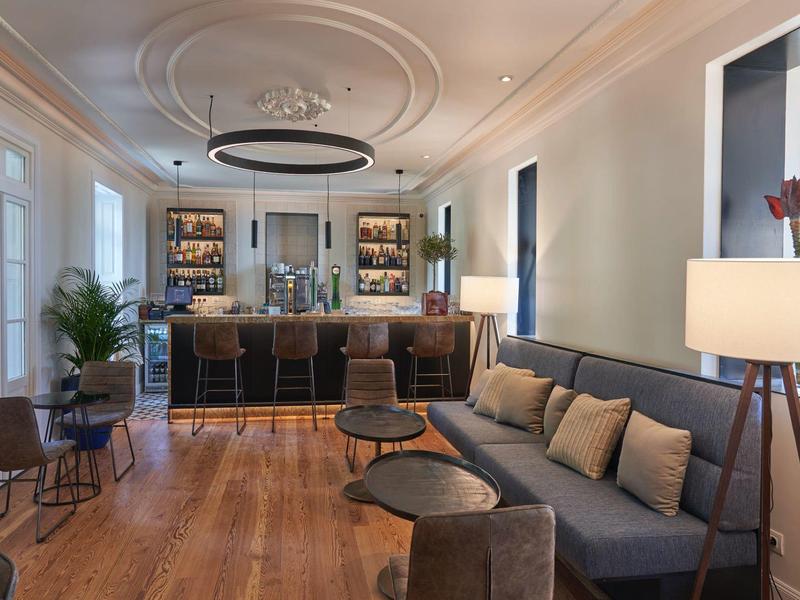 Moderner Wohn- und Essbereich mit dunkelgraßer Couch, Holzparkett und Bartresen mit Hockern.