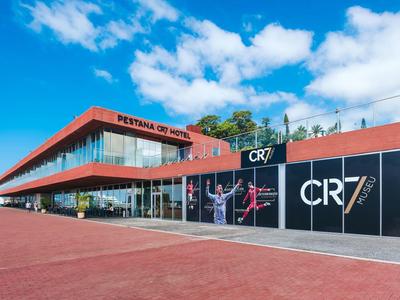 Modernes, rotes Gebäude mit großen Fenstern, blauer Himmel, Aufschrift "Festival da Criatividade".