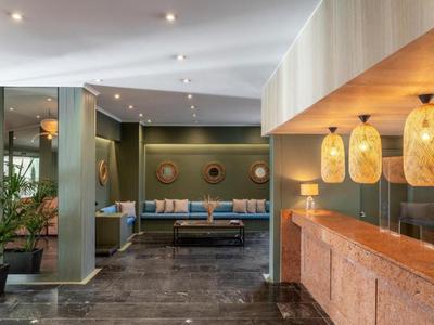 Modern hotel lobby with sofa, plants, and warmly lit reception area.