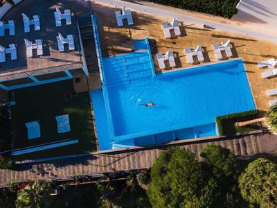 Rechteckiger Pool mit blauer Wasseroberfläche, umgeben von weißen und blauen Liegestühlen.