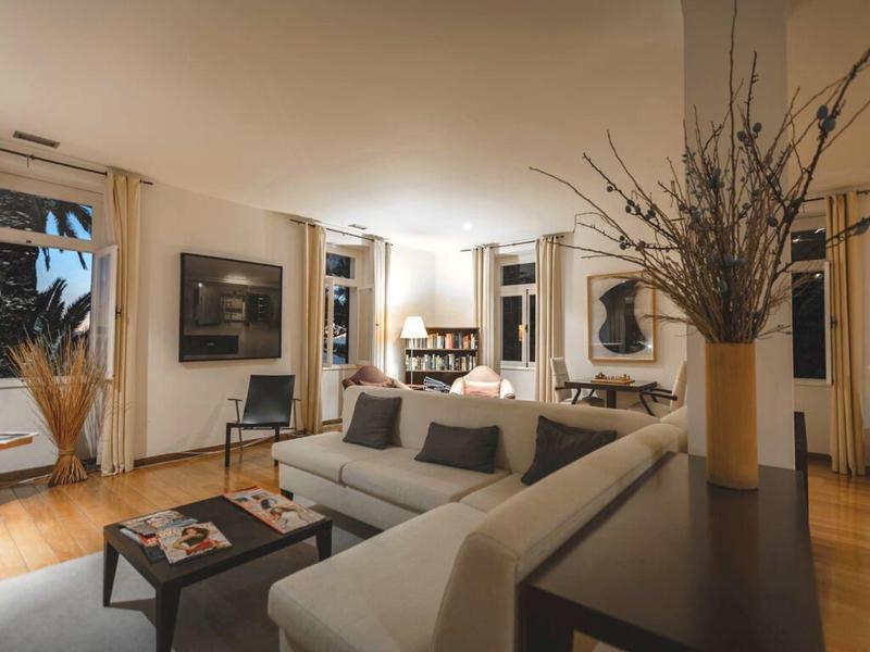 Soggiorno luminoso con arredi moderni, grande divano e rami decorativi in primo piano.