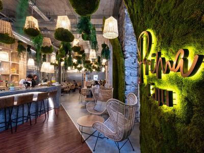 Moderner Café-Innenraum mit Mooswand, gemütlichen Sitzgelegenheiten und warmem Licht.