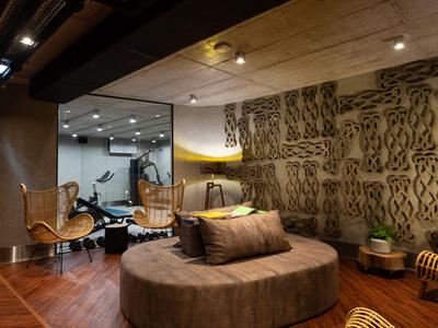 Moderne hotelkamer met ronde grijze bank, decoratieve muur en rieten stoelen.