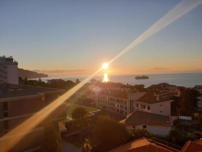 Tramonto su una città costiera con vista sul mare e una nave da crociera.