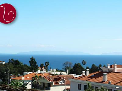 Vista sul mare con case e palme in primo piano sotto un cielo limpido.