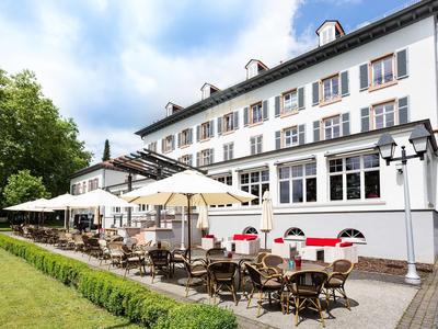 Außenansicht eines großen Hotels mit Terrasse und Sonnenschirmen an einem sonnigen Tag