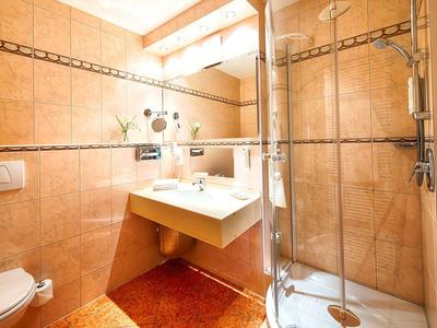 Cozy bathroom with orange tiles, white sink, glass shower, and toilet.