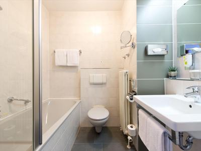 Kompaktes Badezimmer mit Badewanne, Toilette und Waschbecken in hellen, neutralen Farben.