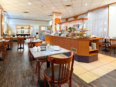 Hell beleuchteter Frühstücksraum mit Buffet und gedeckten Tischen in einem Hotel.