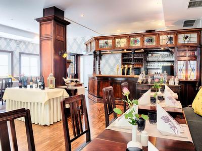 Elegantes Restaurant mit Holzmöbeln, dekorierten Tischen und einer stilvollen Bar im Hintergrund.