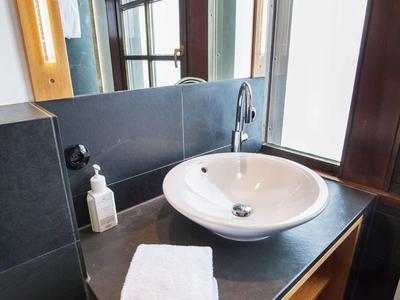 Badezimmerwaschbecken mit Handtüchern und Seifenspender neben großen Fenstern.