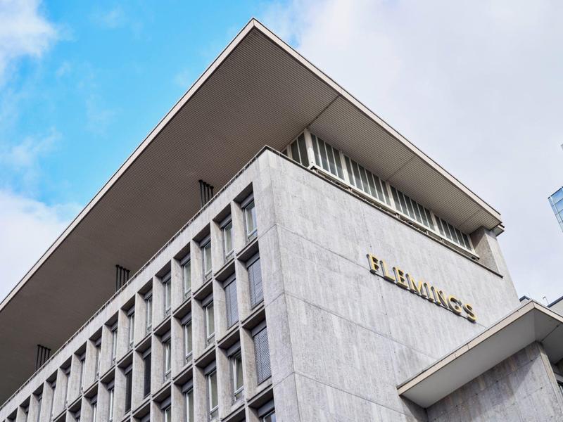 Bâtiment d'hôtel moderne à plusieurs étages avec toits angulaires et grand logo sur la façade.