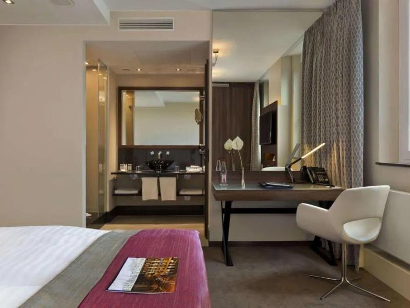 Chambre d'hôtel moderne avec bureau et salle de bain ouverte.