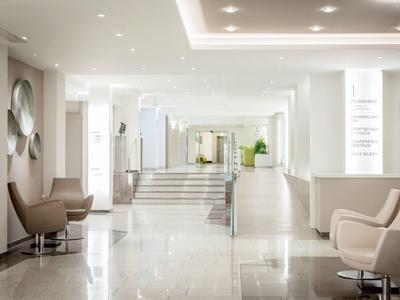 Heller, geräumiger Hotel-Flur mit modernen Sesseln und Stufen zu einem weiteren Bereich.