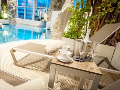 Lettini con asciugamani e tavolo con champagne e tazze accanto a una piscina.