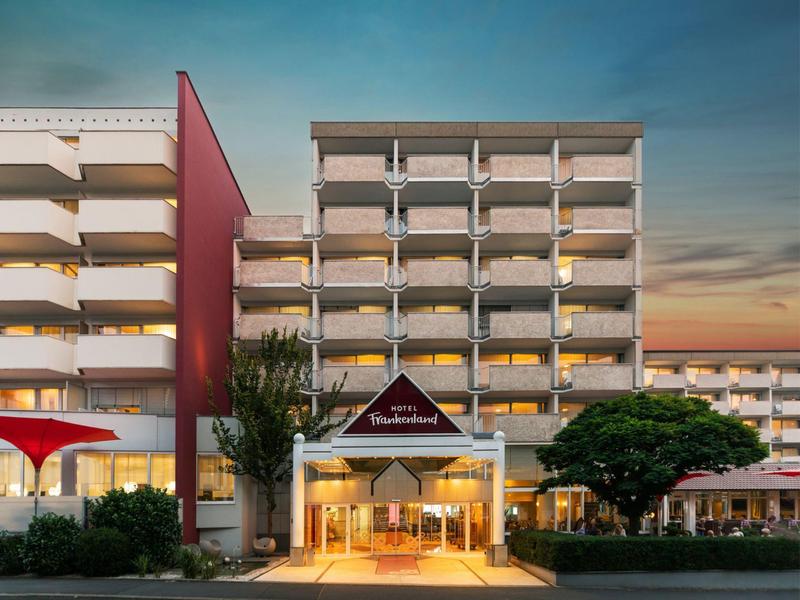 Edificio alberghiero su più piani con ingresso illuminato al tramonto.