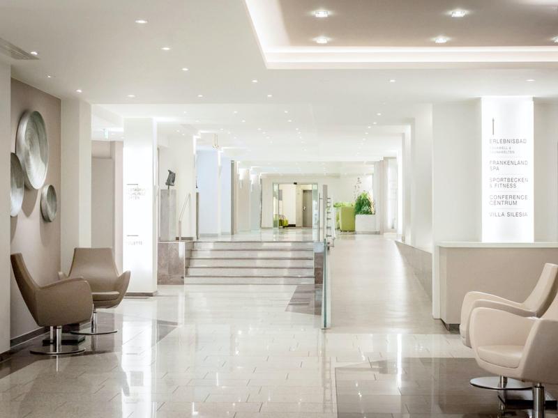 Corridoio di hotel moderno e luminoso con poltrone comode e pavimento in marmo lucido.