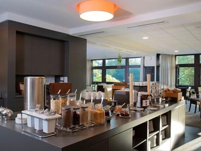 Strefa bufetu z różnymi produktami śniadaniowymi i miejscami do siedzenia w jasnym pomieszczeniu.