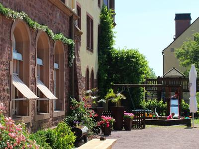 Cortile di un hotel con fiori, panchine e una bicicletta per bambini su una superficie lastricata.