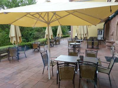 Leere Terrasse mit Tischen und Stühlen unter großen Sonnenschirmen im Freien.