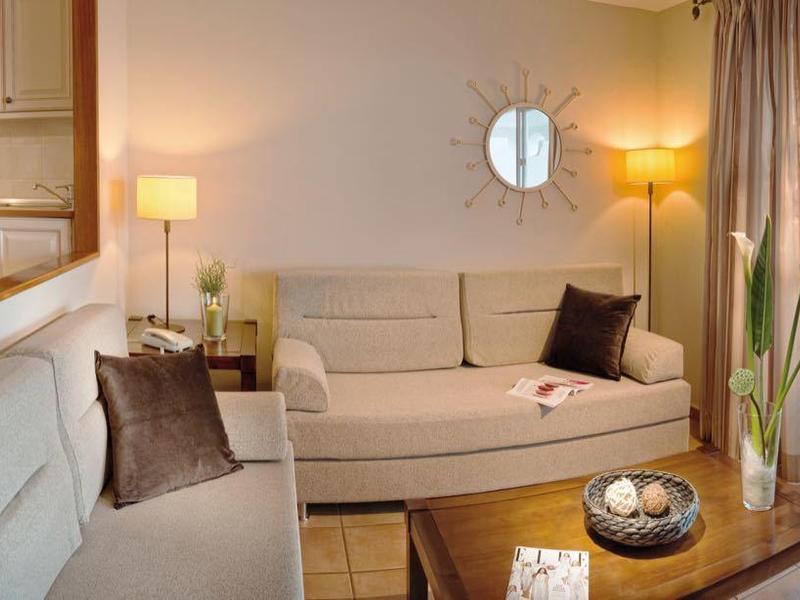 Helles Wohnzimmer mit weißer Polstermöblierung und Zugang zu Balkon mit Meerblick.