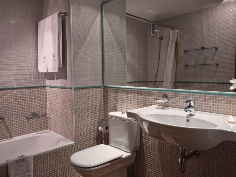 Kompaktes Badezimmer mit Waschbecken, Toilette, Dusche und Handtüchern an der Wand.