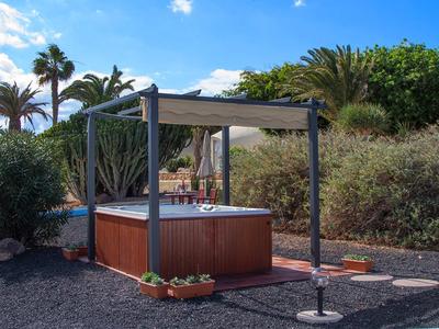 Outdoor-Whirlpool unter Pavillon mit Palmen und blauer Himmel im Hintergrund