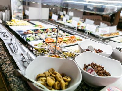 Buffet mit verschiedenen Speisen in weißen Schalen auf einer Granit-Arbeitsplatte.