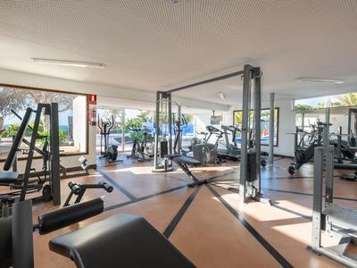 Helles Fitnessstudio mit modernen Geräten und großen Fenstern mit Meerblick.