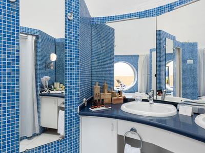 Modernes Badezimmer mit blauen Fliesen, runden Spiegeln und weißen Waschbecken.