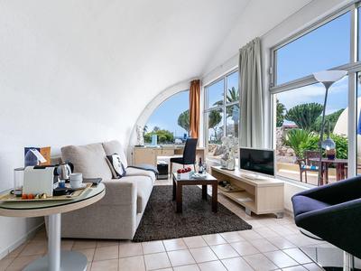 Helles Wohnzimmer mit großem Fenster, gemütlichen Sofas und Blick auf Terrasse und Garten.