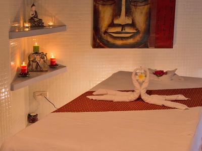 Massagebett mit dekoriertem Handtuch und Kerzen in einem warm beleuchteten Raum