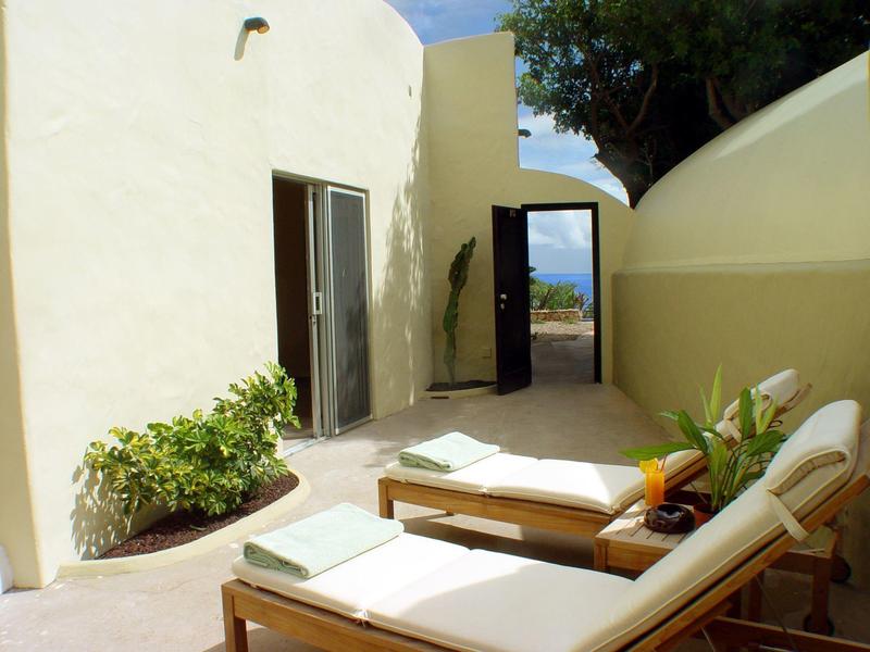 Zwei Liegestühle mit Handtüchern auf einer Terrasse mit Blick aufs Meer.