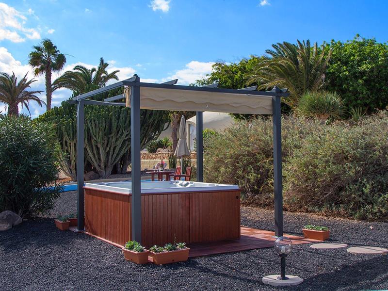 Outdoor-Whirlpool unter Pavillon mit Palmen und blauer Himmel im Hintergrund