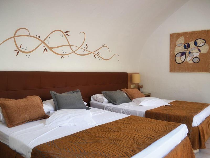 Zwei Einzelbetten mit braunen Decken und Kissen in einem hellen, gemütlichen Hotelzimmer.