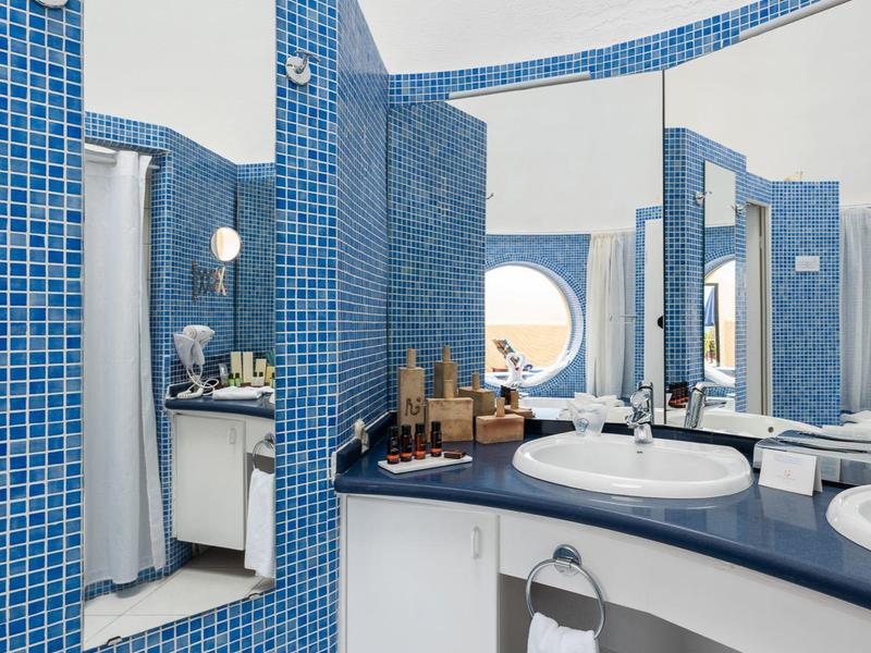 Modernes Badezimmer mit blauen Fliesen, runden Spiegeln und weißen Waschbecken.