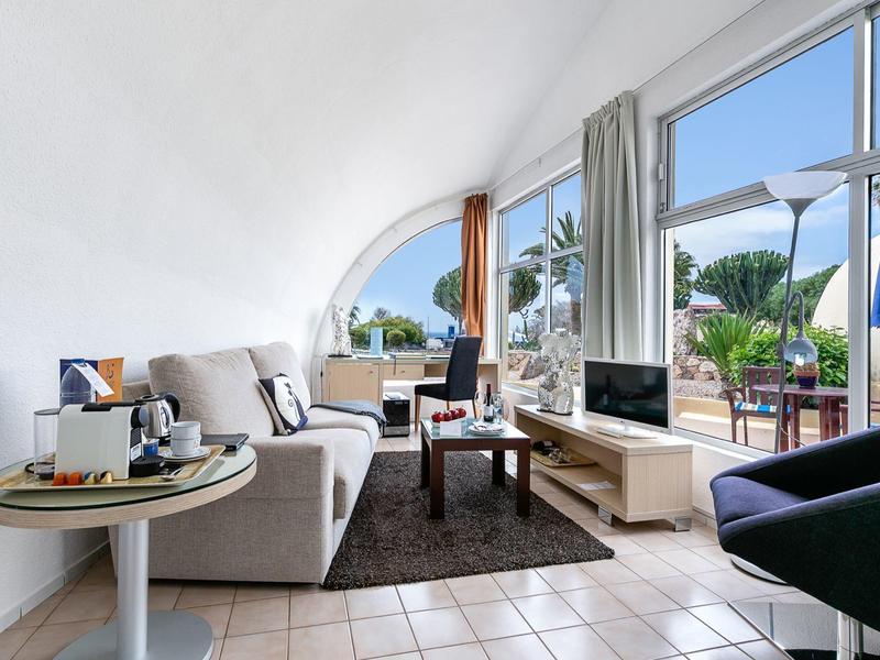 Helles Wohnzimmer mit großem Fenster, gemütlichen Sofas und Blick auf Terrasse und Garten.