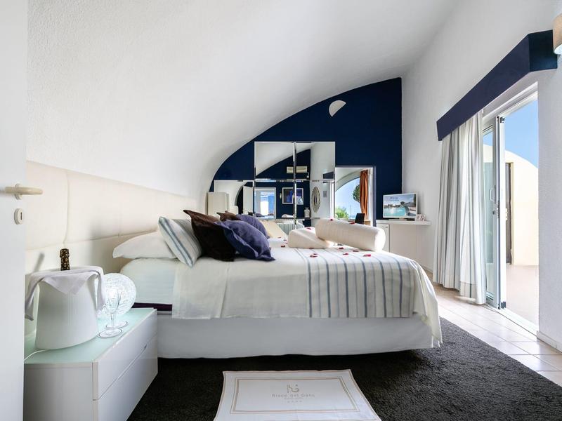 Helles Schlafzimmer mit Dachschräge, großem Bett und Zugang zu Terrasse oder Balkon.