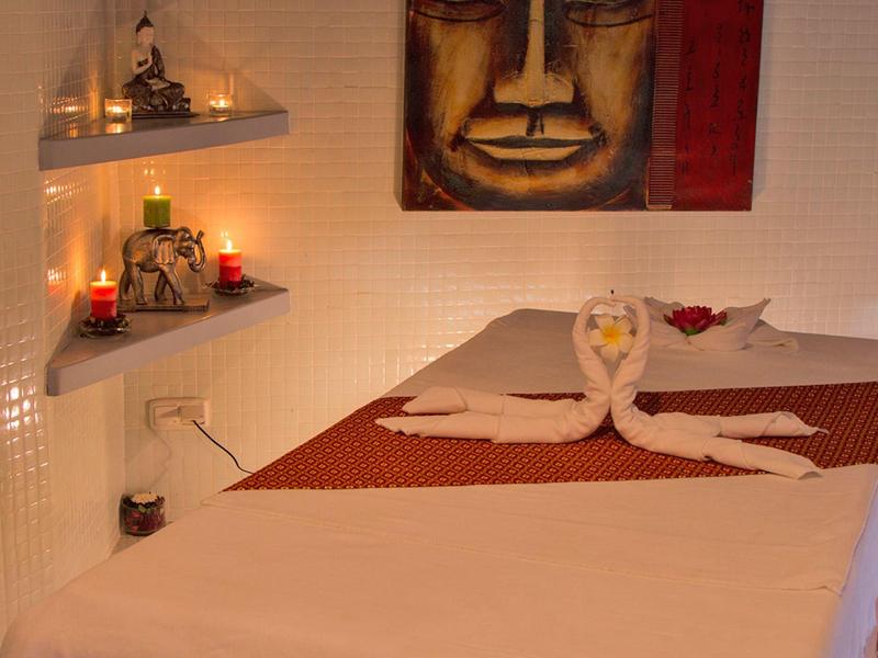 Massagebett mit dekoriertem Handtuch und Kerzen in einem warm beleuchteten Raum