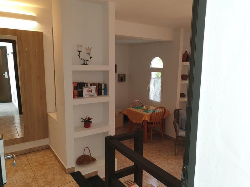 Innenansicht eines Raums mit weiß gestrichenen Wänden, Regalen und braunem Holzstuhl vor Fenster.