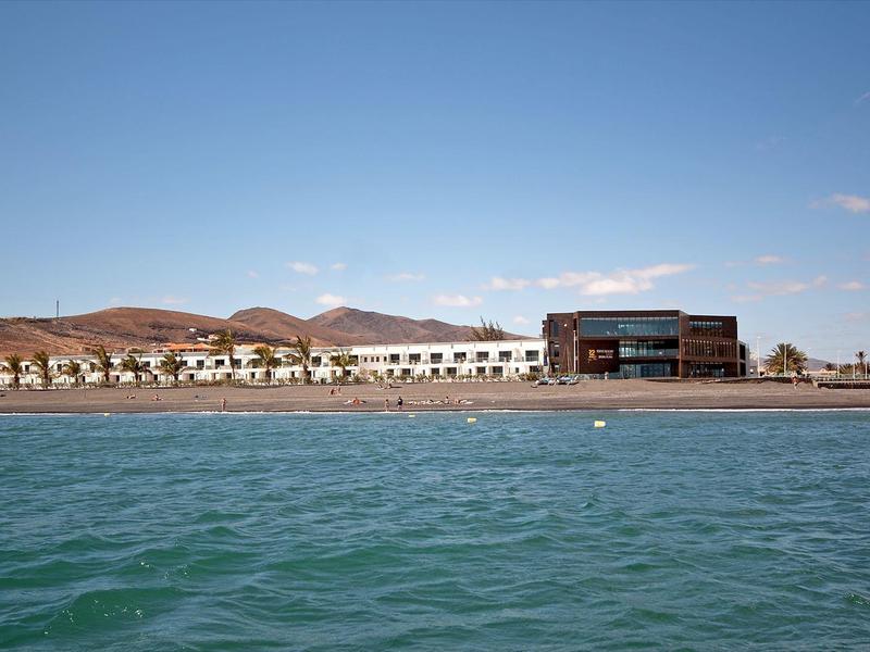 Strandresort met moderne gebouwen en ligstoelen bij kalme zee onder blauwe lucht