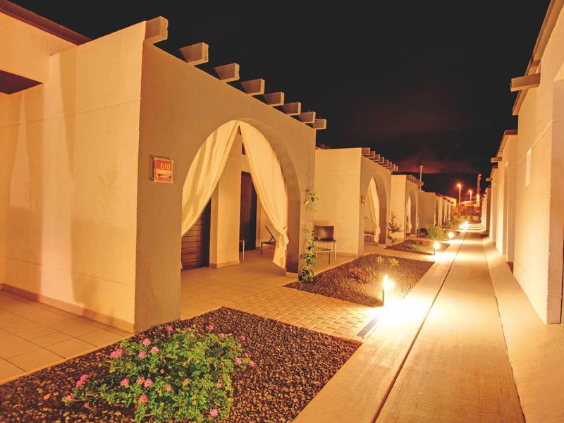 Verlicht hotelpad met witte muren en stenen tuin 's nachts