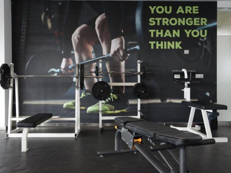 Sportschool met gewichtbank en motiverende poster aan de muur.