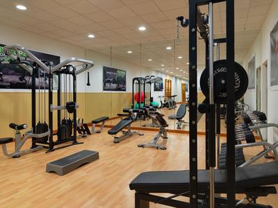 Moderner Fitnessraum mit Trainingsgeräten und Holzfußboden in einem Hotel.