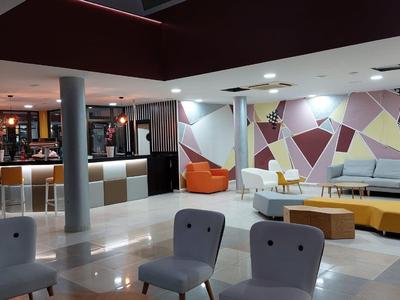 Moderner Lounge-Bereich mit bunten Sitzsäcken, grauen Sesseln, gelben Sofas und geometrischer Wandgestaltung.