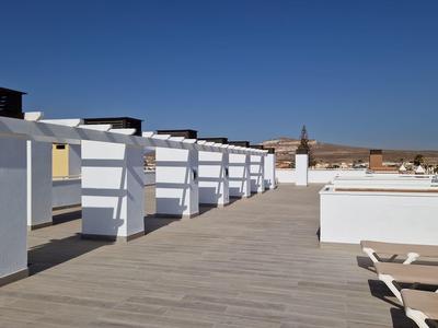 Flachdach mit weißem Geländer, Holzterrasse und blauer Himmel im Hintergrund.