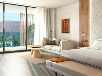 Modernes Hotelzimmer mit Bett, Sofa und Blick auf Berg und See durch große Fenster.