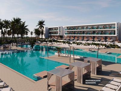 Moderner Hotelkomplex mit großem Pool, Sonnenliegen und Palmen unter bewölktem Himmel.