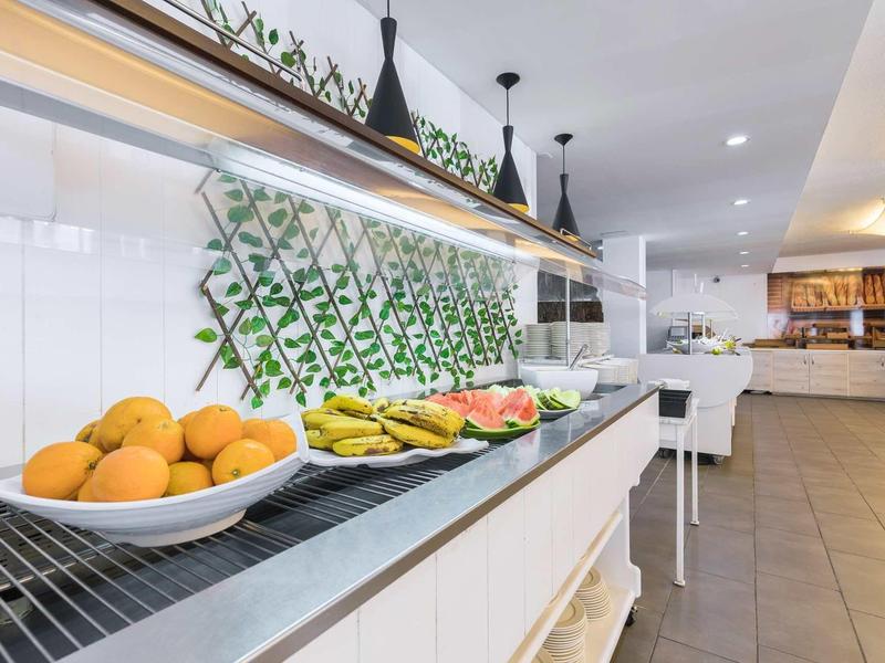 Buffet with fresh fruit on a white counter in a modern dining area.