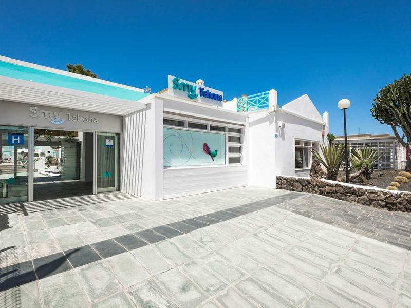 Entrance area of a modern hotel with white facade and blue sky.
